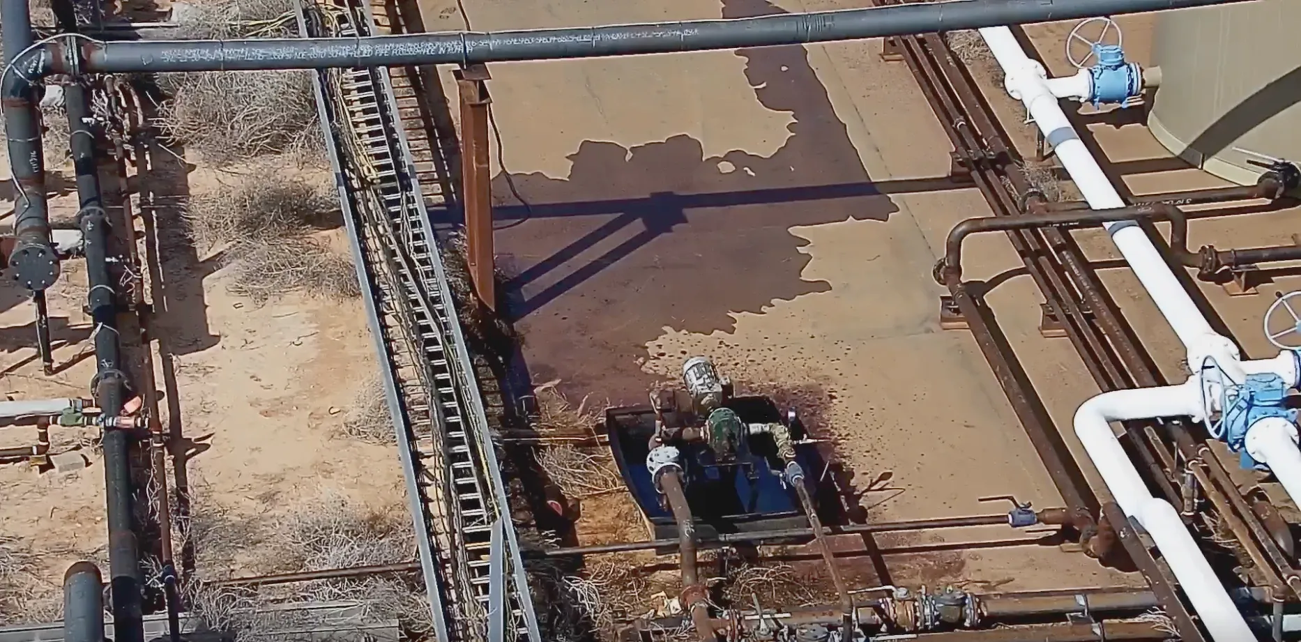 Raw camera view of a small liquid puddle around tank piping at a Permian CTB