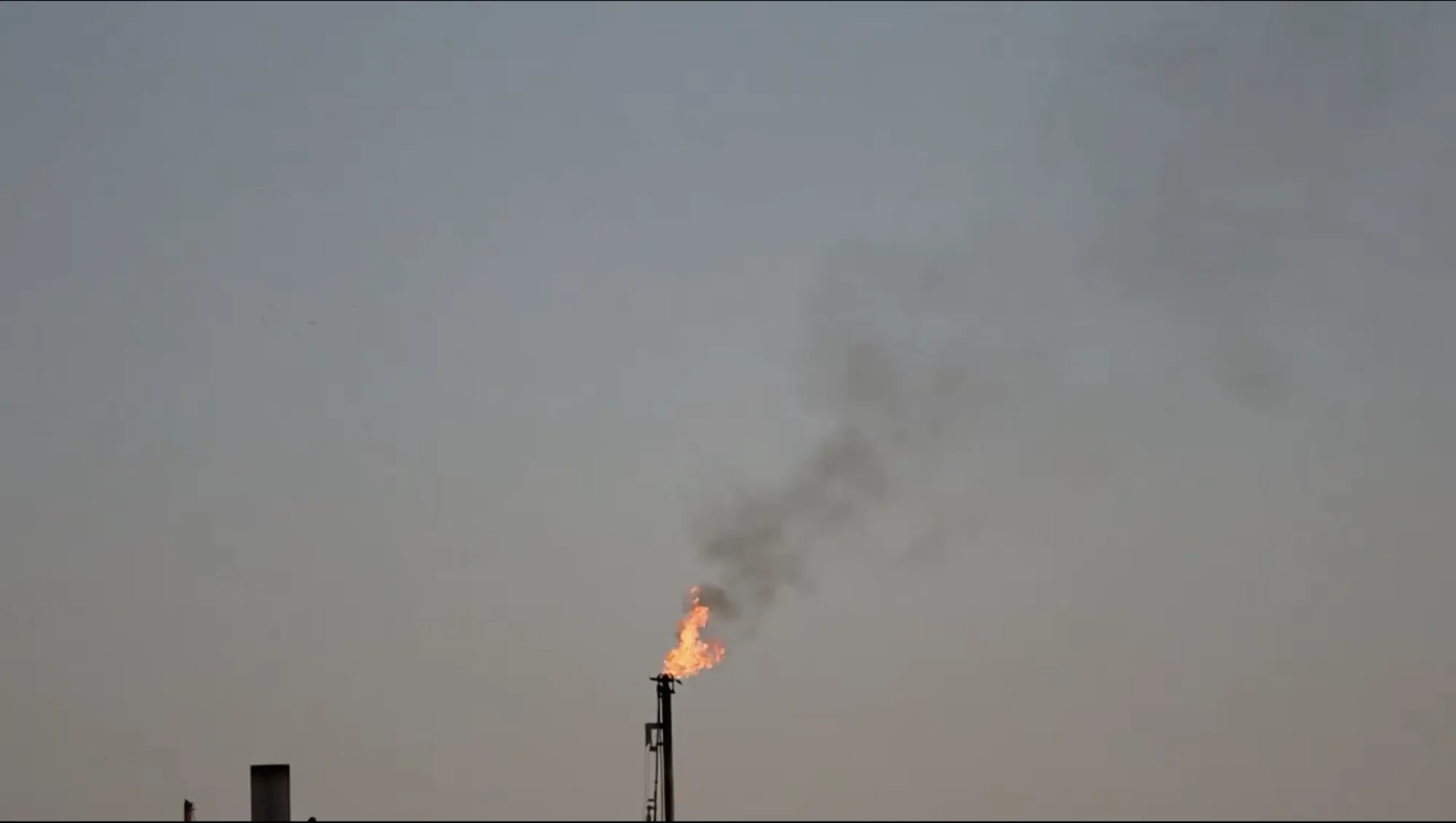 Raw camera view of a flare stack with visible flame and smoke plume