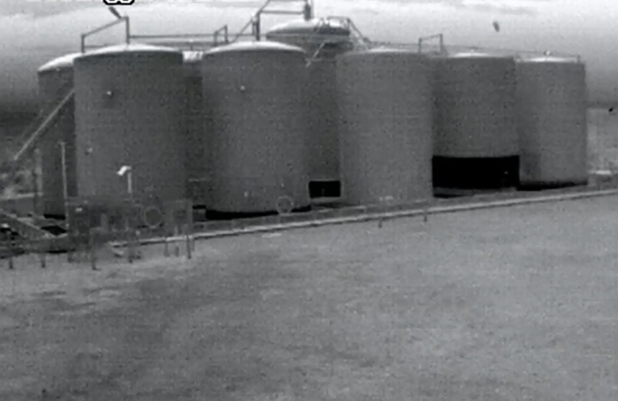 Raw FLIR thermal image of a tank battery showing fill levels by surface temperature contrast