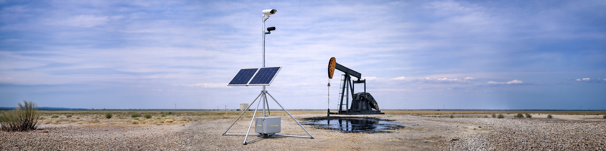 Self-contained solar powered Remote Pumper skid deployed at a remote stripper well site with pumpjack in background