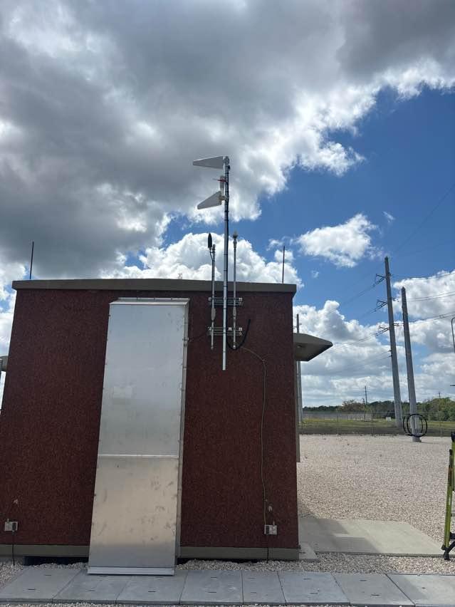 Two log-periodic donor antennas mounted on a mast at the corner of a solar plant substation control building, aimed to capture macro cellular signal for the in-building CEL-FI GO G43 system